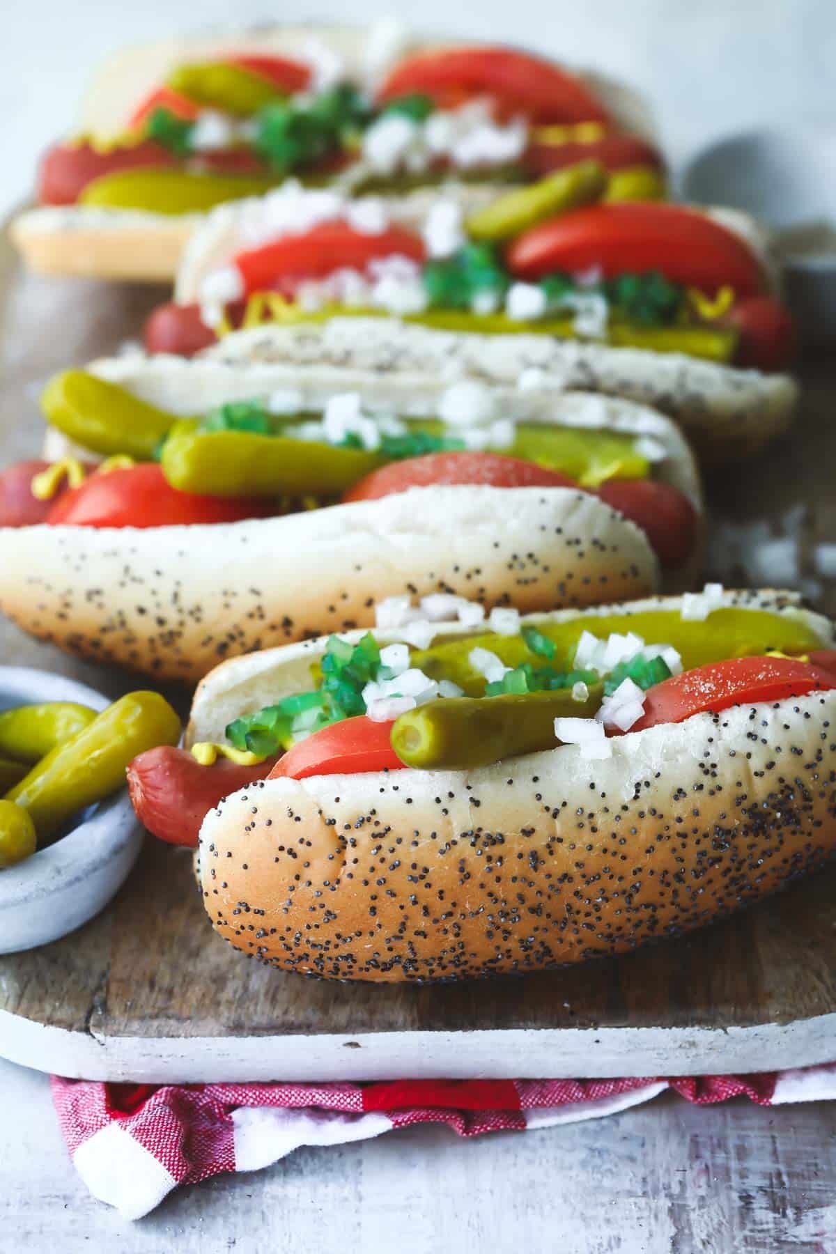 Four Chicago style hot dogs on a wooden platter.