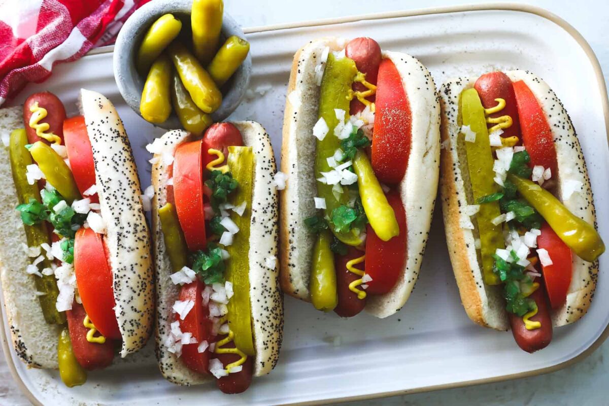 Four Chicago style hot dogs on a platter.