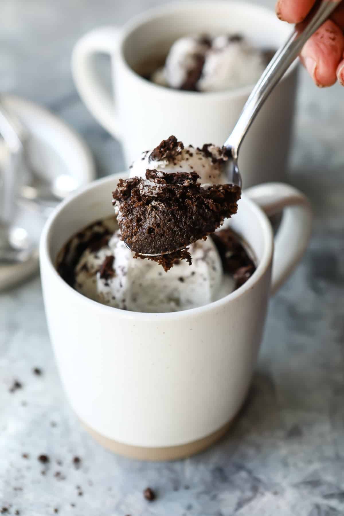 Someone taking a spoonful out of an oreo mug cake.