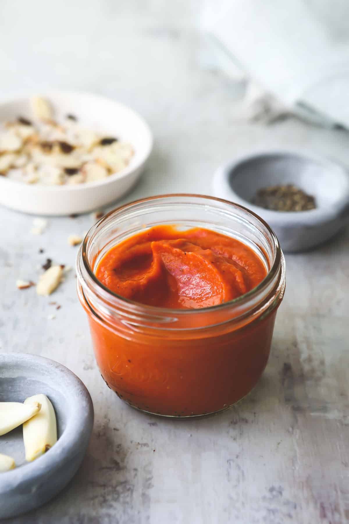 A small clear jar of Romesco sauce.