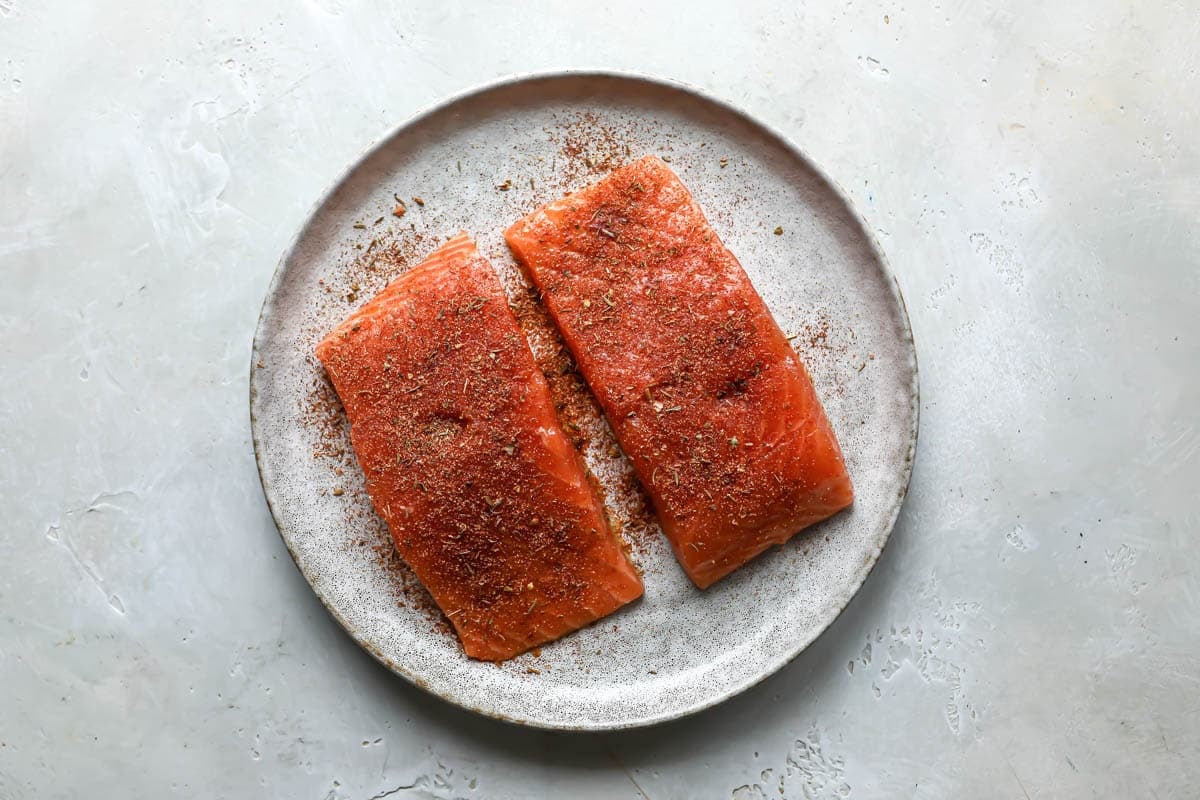 Seasoned salmon on a plate before being air fried.