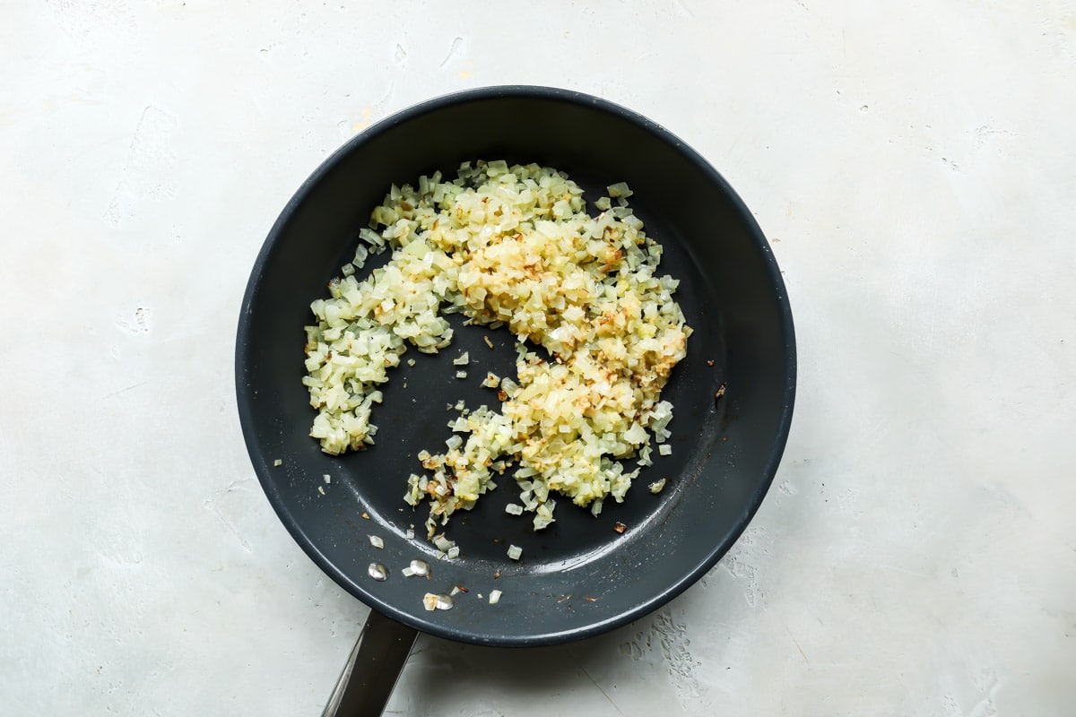 Onions cooking in butter and oil in a skillet.