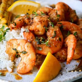 A plate of cajun shrimp, white rice, and corn on the cob.