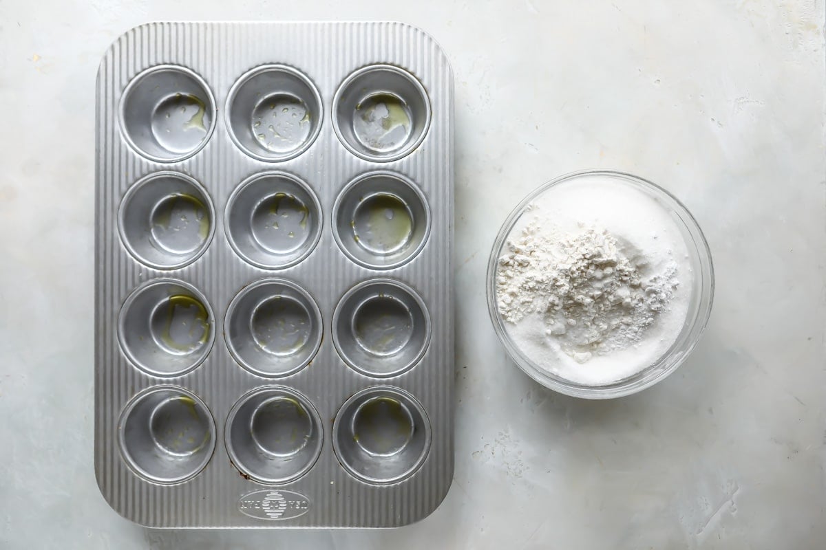 Dry ingredients for muffins next to an empty muffin tin.