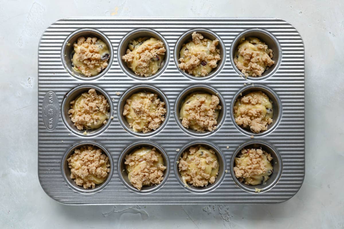 Cranberry orange muffin batter in a muffin pan.