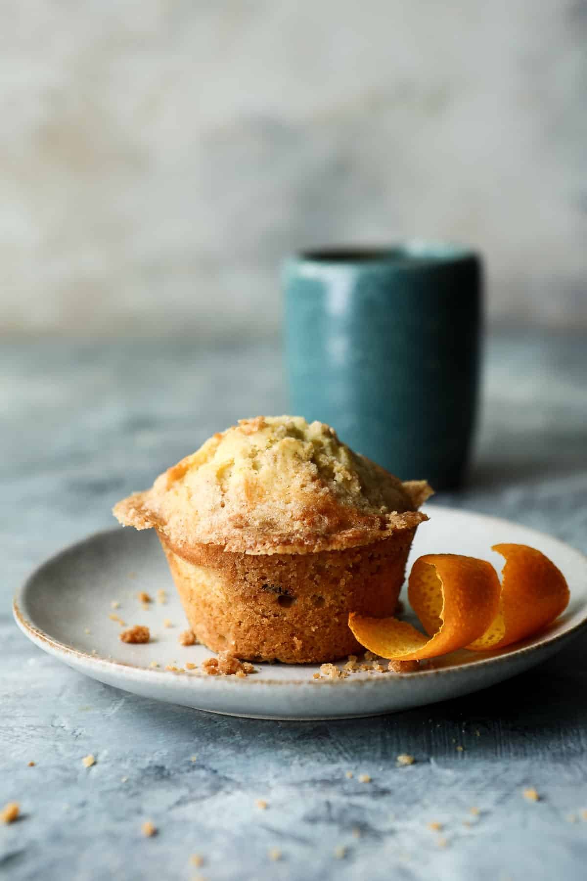 A cranberry muffin on a plate with coffee nearby.