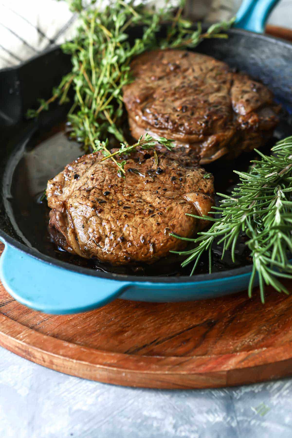 Two filets in a teal skillet.