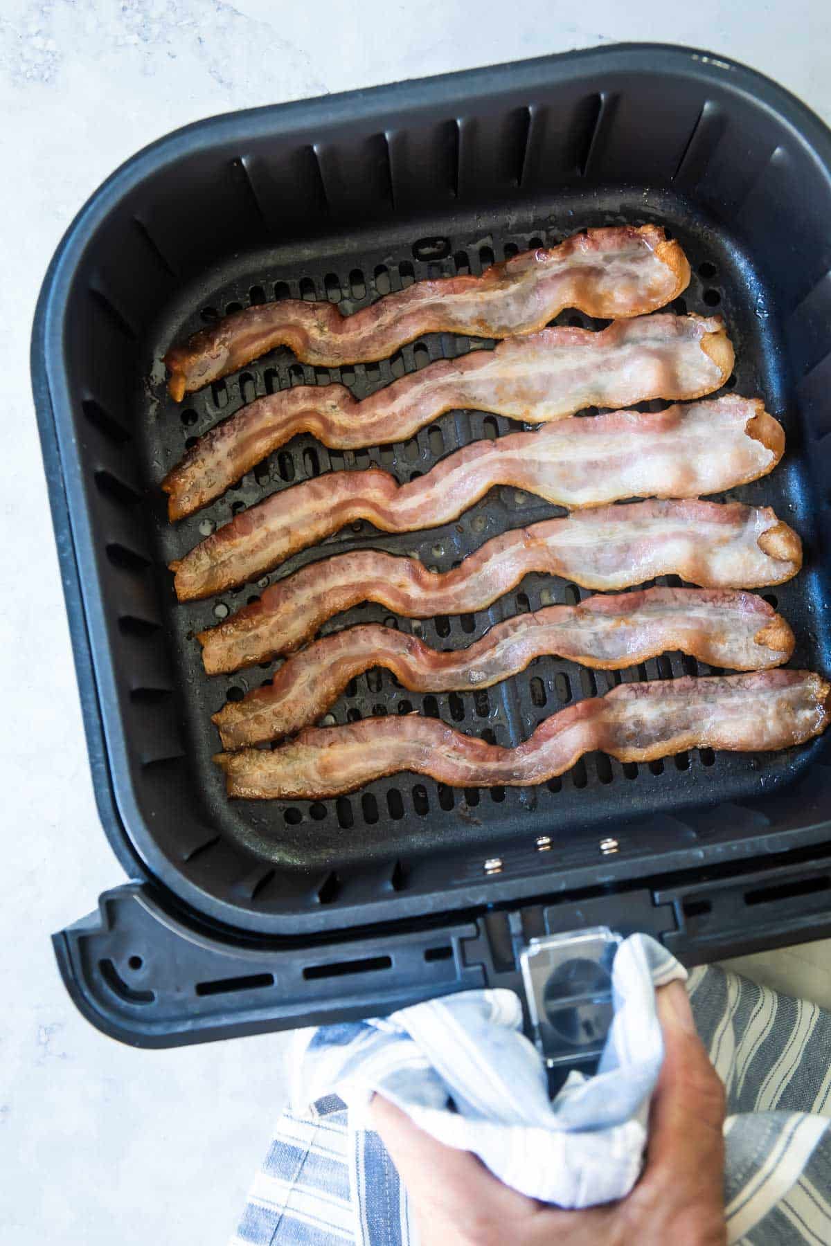 Bacon in an air fryer basket.