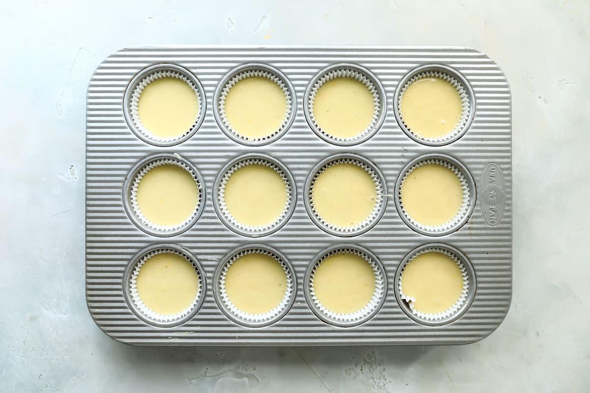 Lemon muffin batter unbaked in a muffin tin.