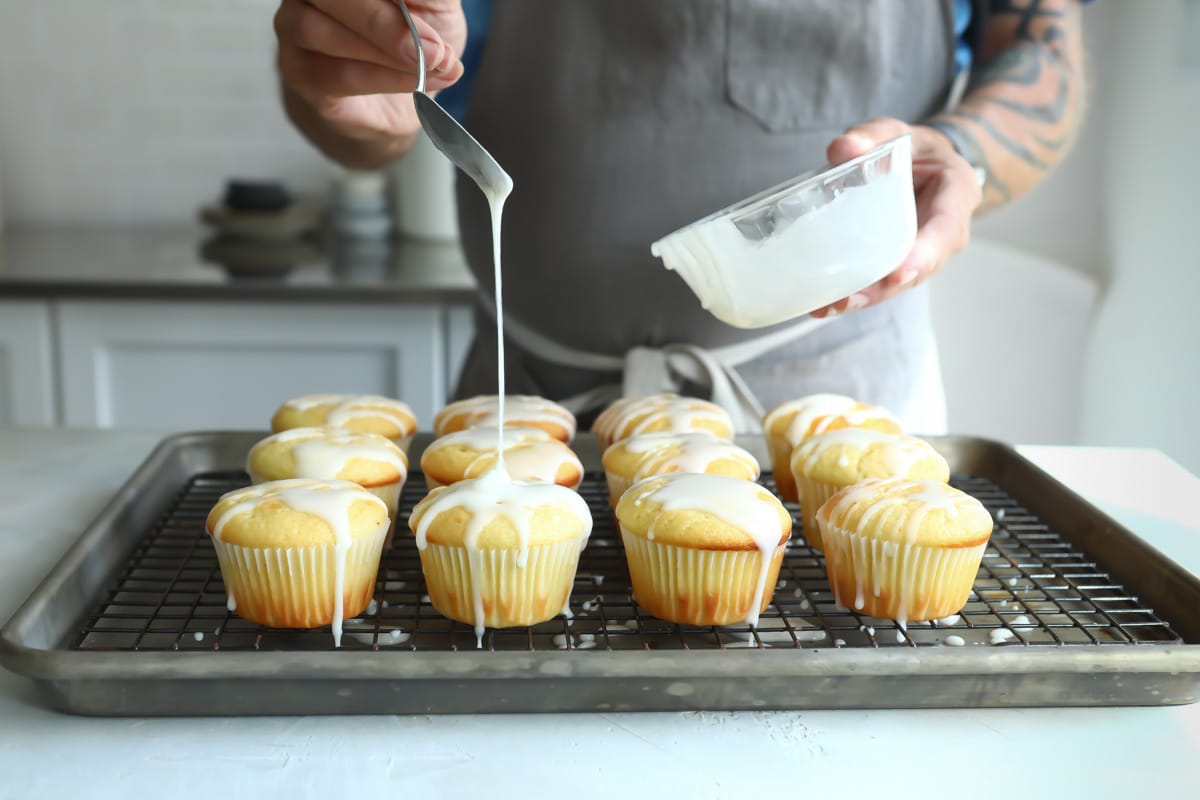 Drizzling a lemon glaze over lemon muffins.