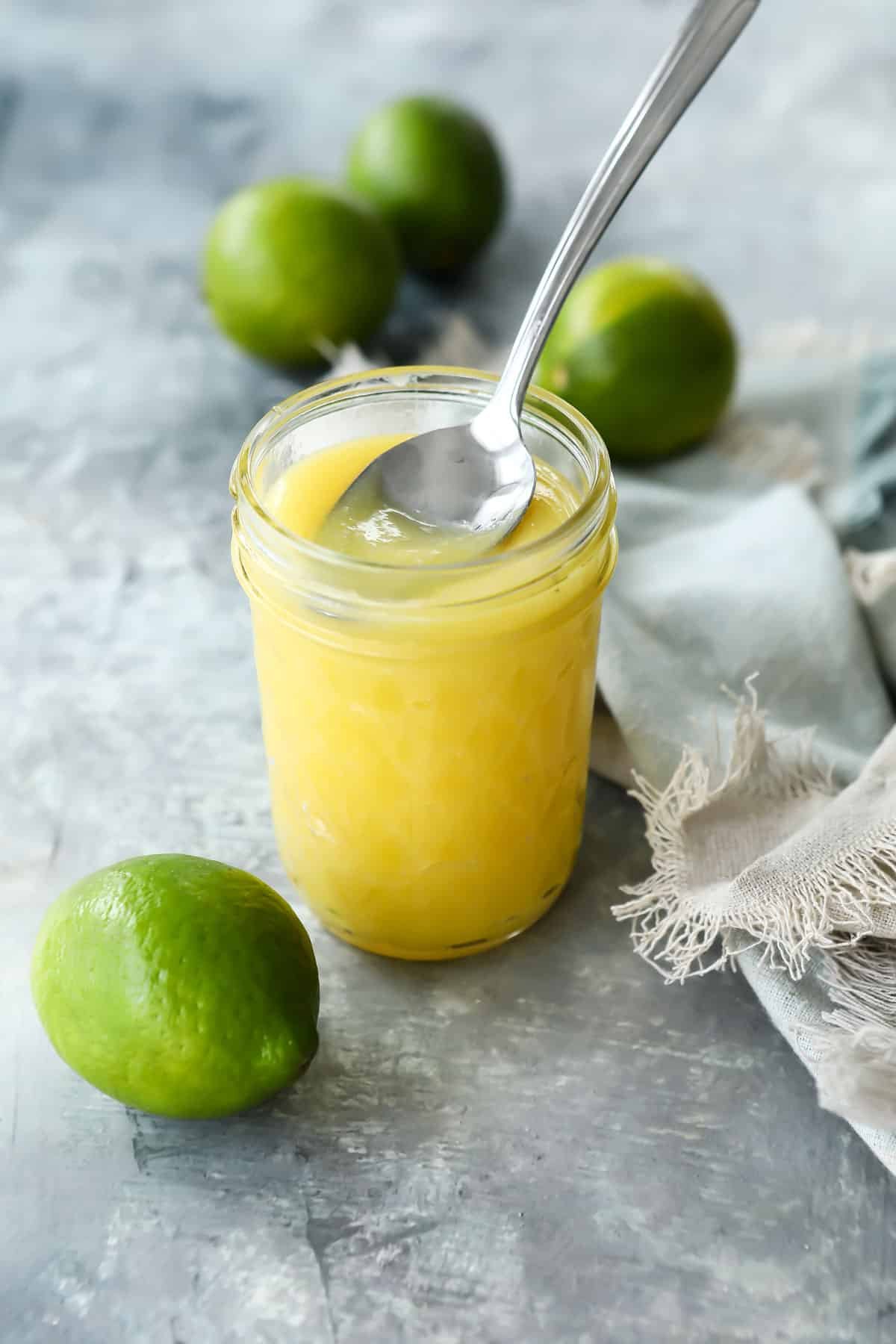 A jar of lime curd with a spoon scooping some out.