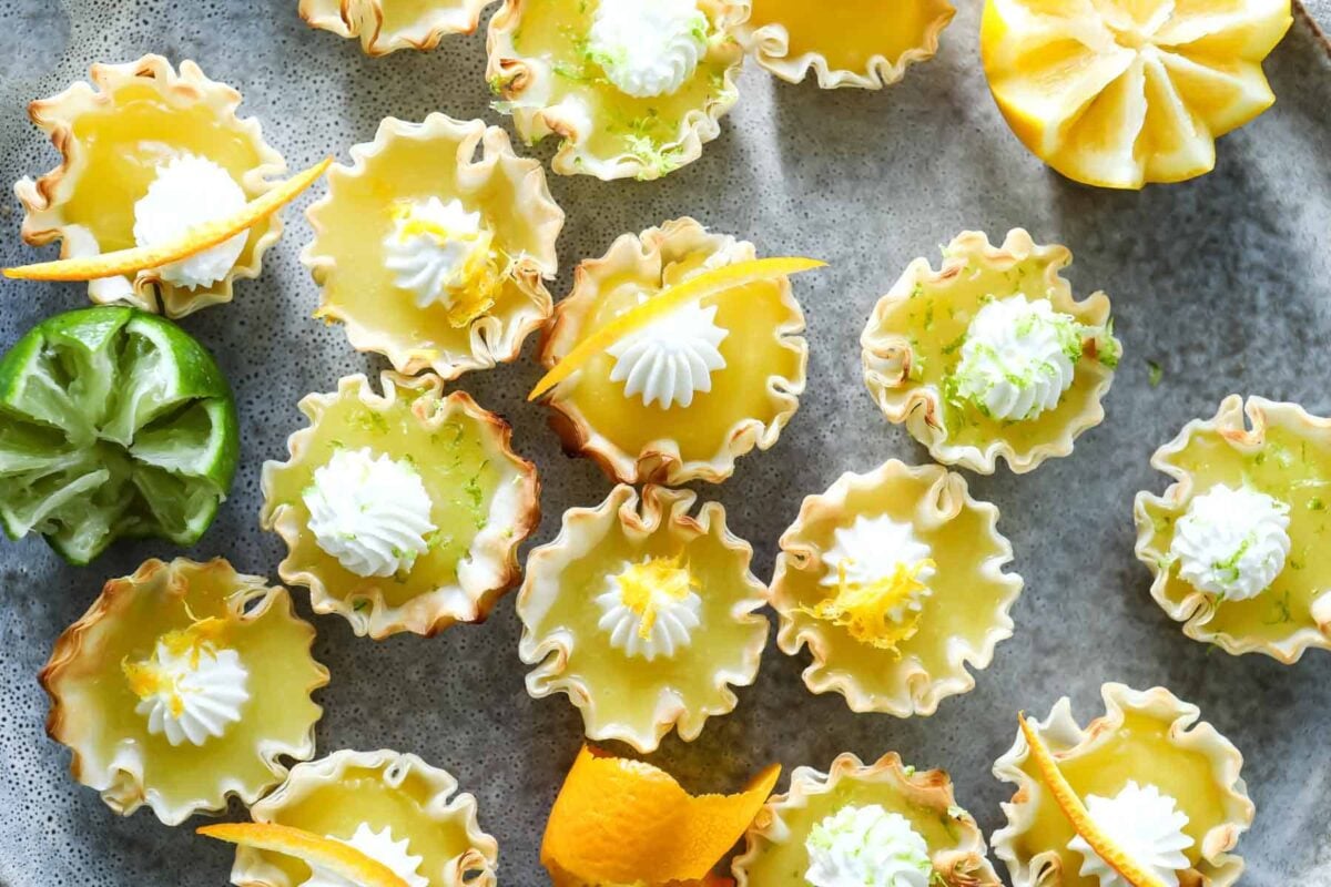 Orange, lemon and lime curd tartlets on a gray plate.