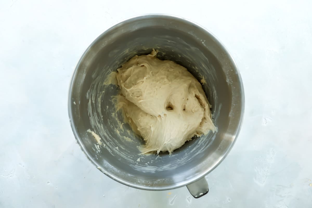 Dough for soft yeast dinner rolls in a silver mixing bowl.