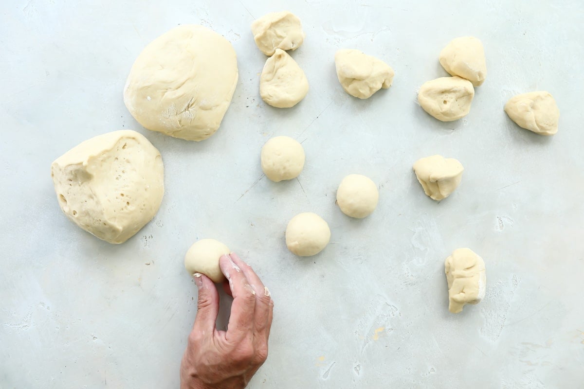 Someone rolling dough for soft yeast dinner rolls into small balls.