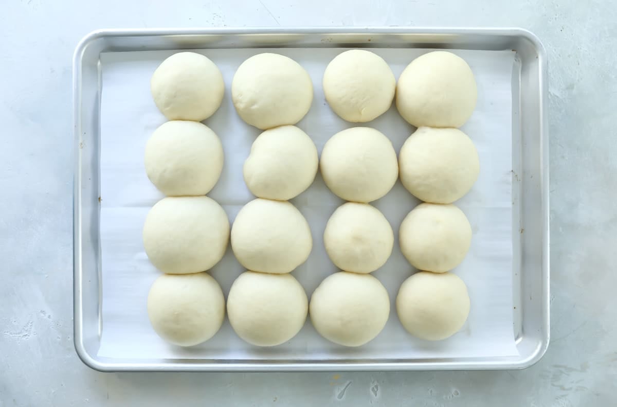 Soft yeast dinner rolls on a baking sheet before being baked.