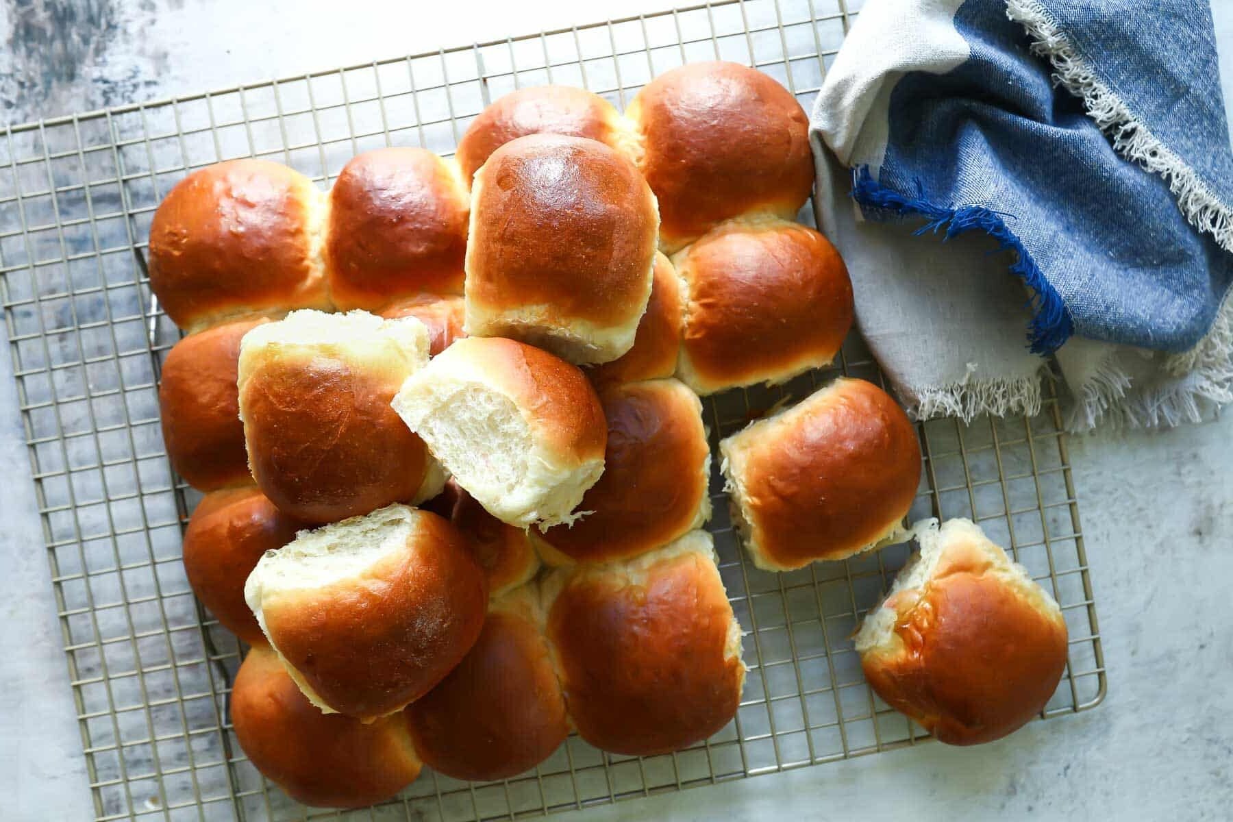 A cooling rack with soft yeast dinner rolls on it.