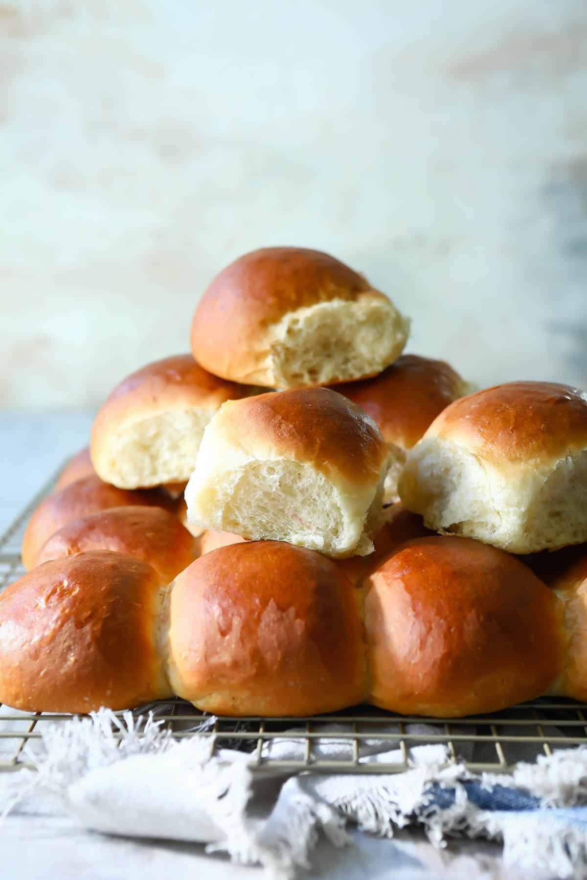 A cooling rack with soft yeast dinner rolls on it.