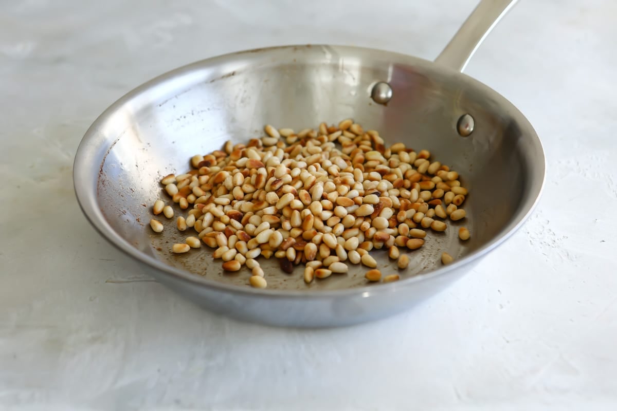 Toasting pine nuts in a skillet.