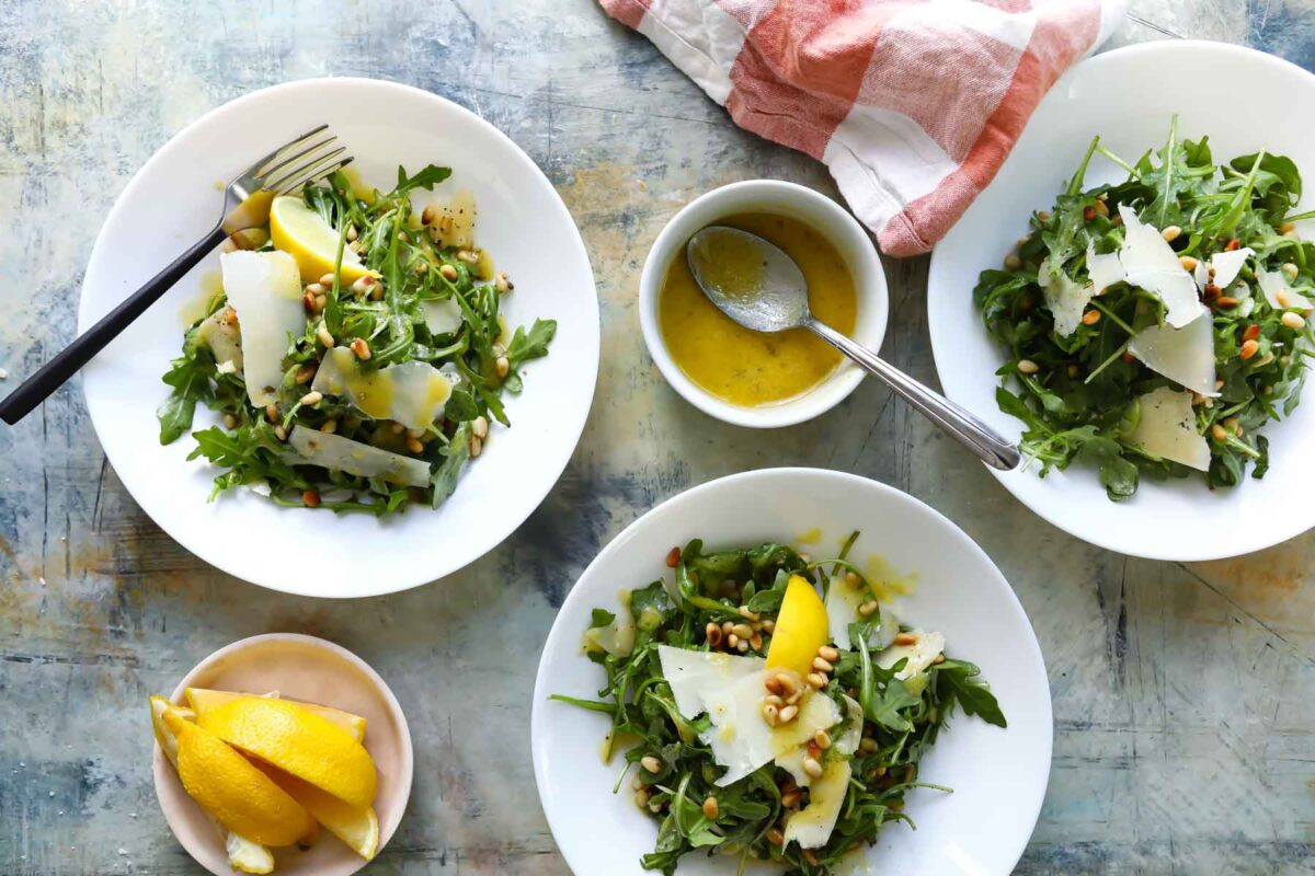 Bowls of arugula salad with pine nuts.