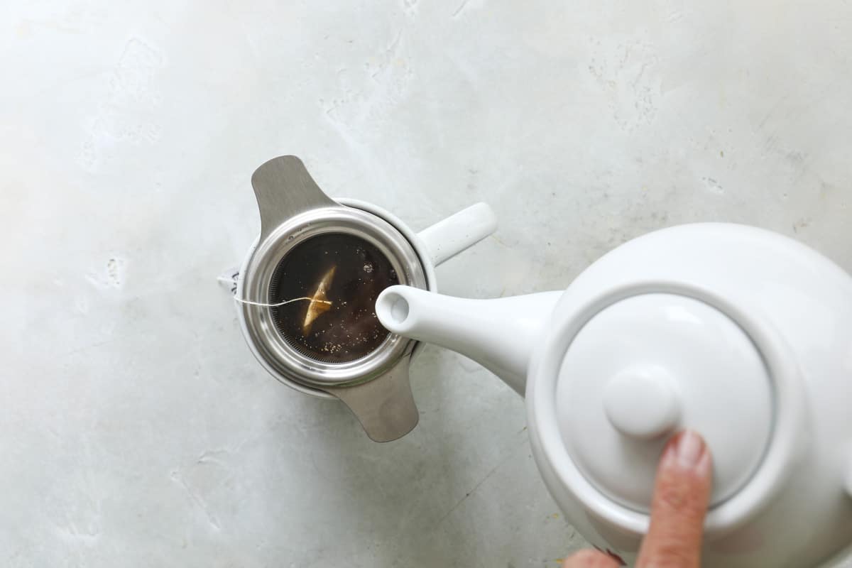 Pouring boiling water into a cup of masala chai.