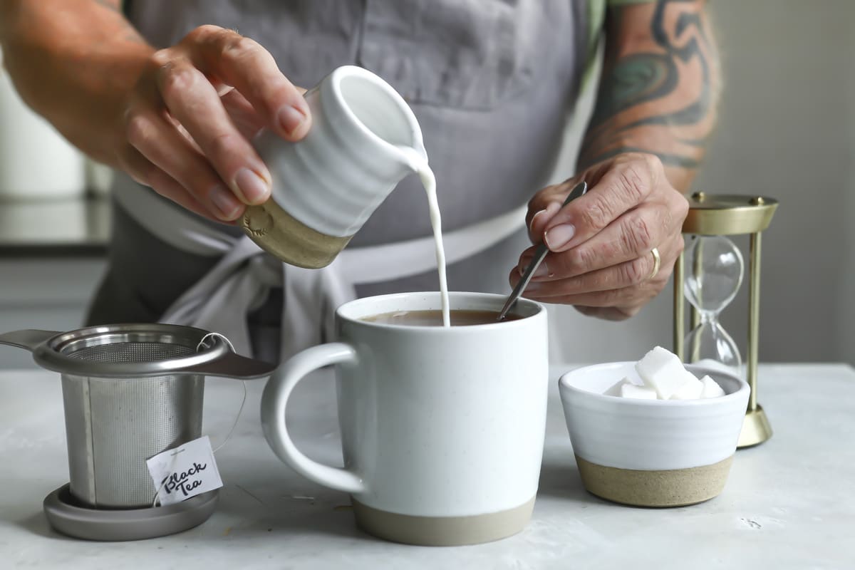 Pouring milk into a cup of masala chai.