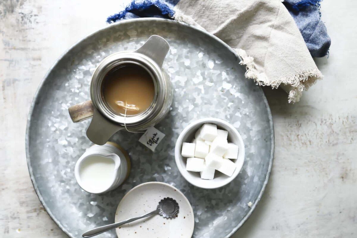 A tray of masala chai tea with sugar, milk, and a timer.