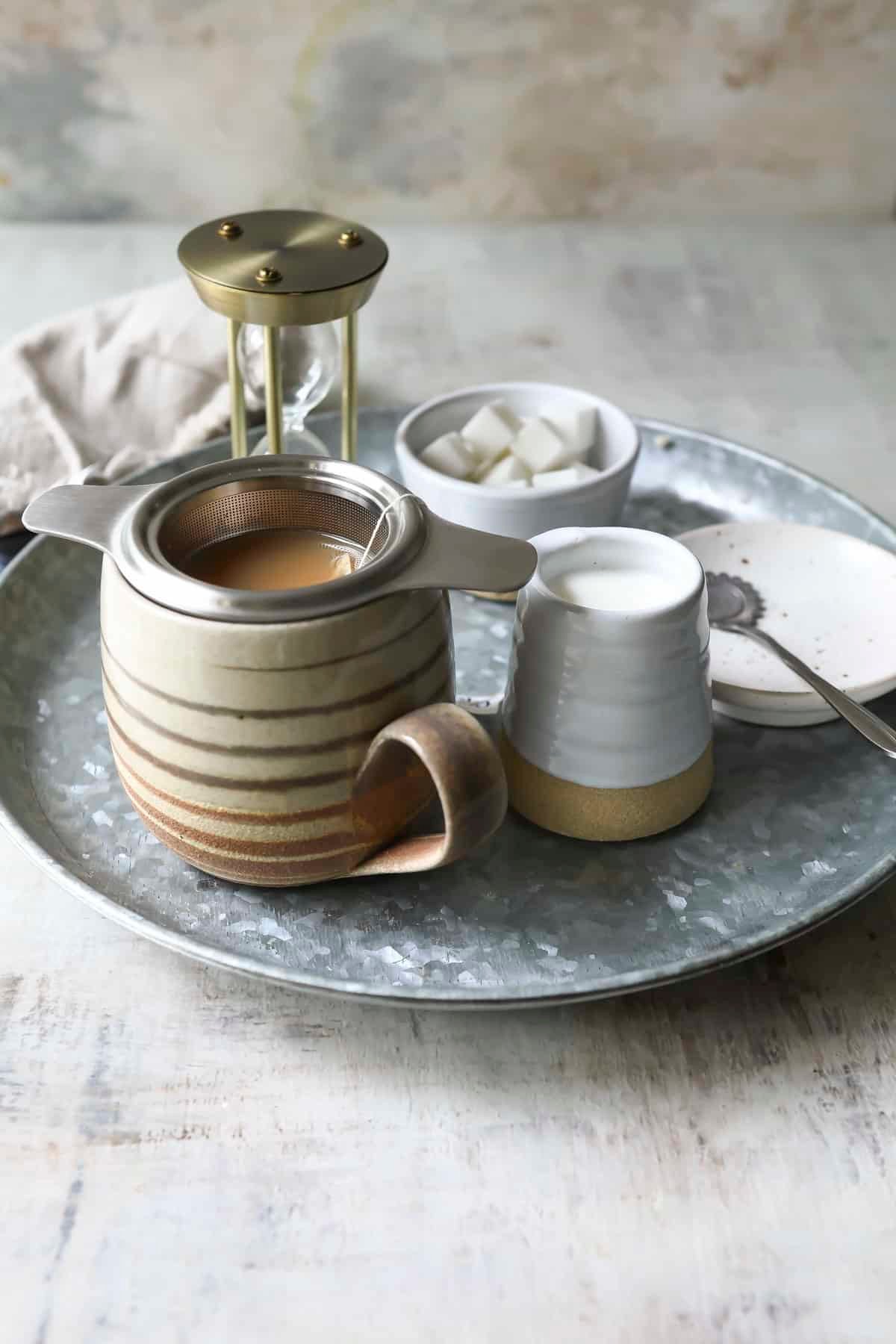 A tray of masala chai tea with sugar, milk, and a timer.