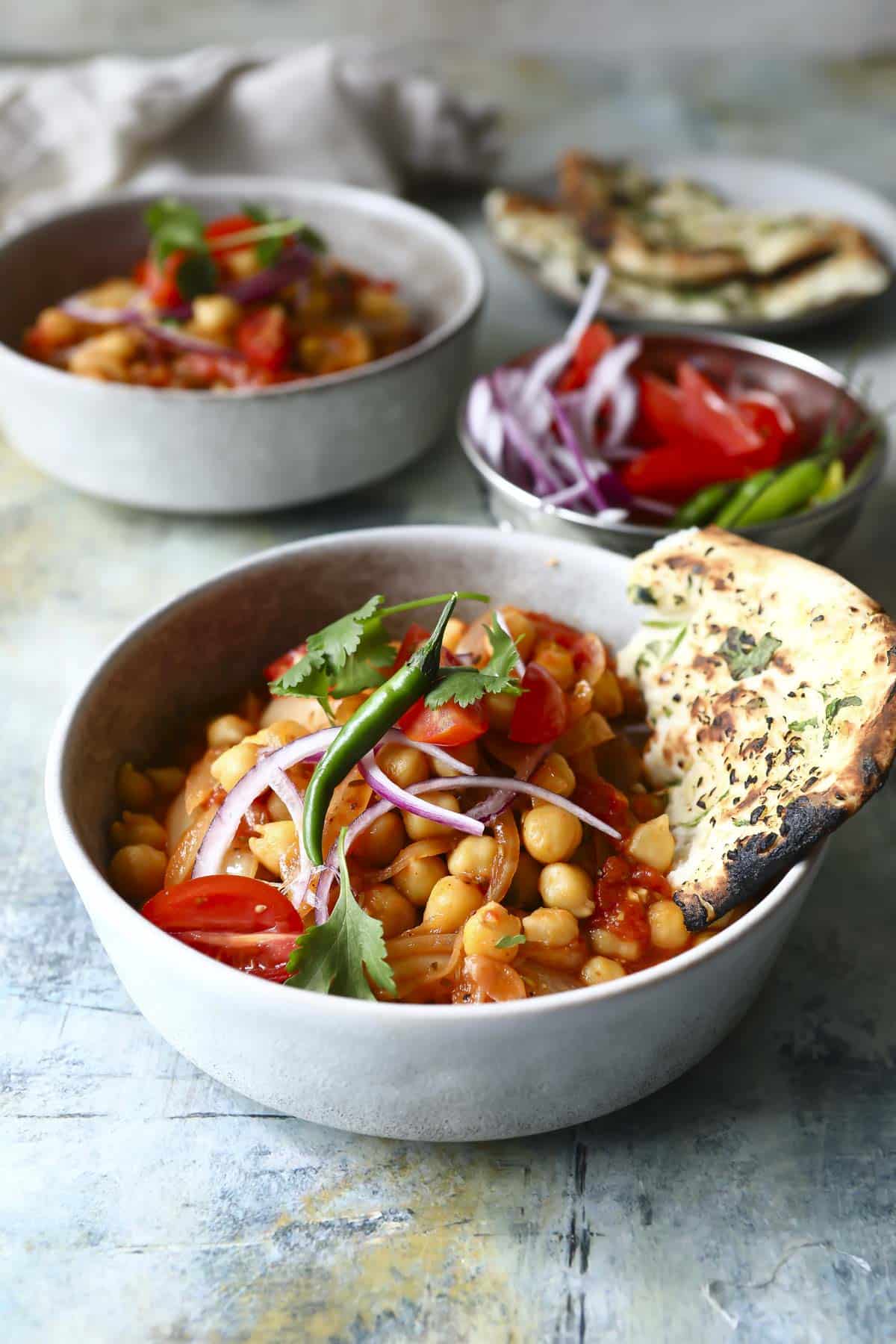 Bowls of chana masala with naan.