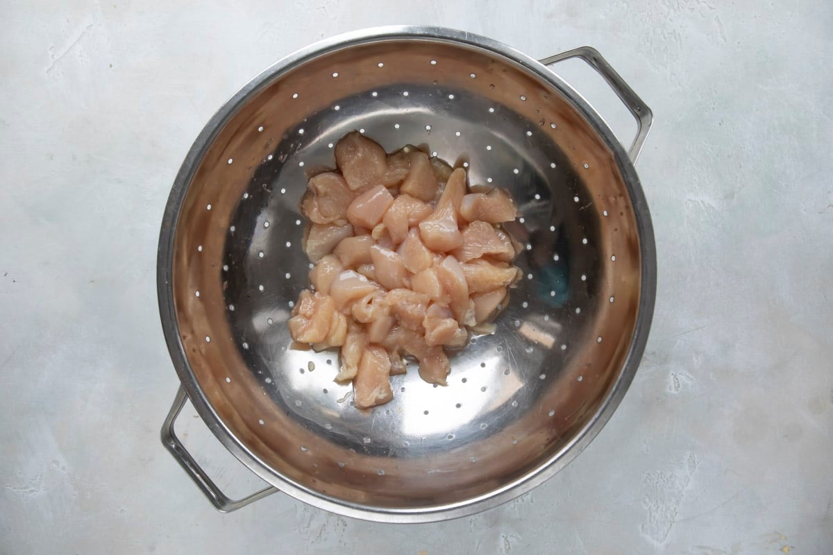 Rinsing chicken in a colander.