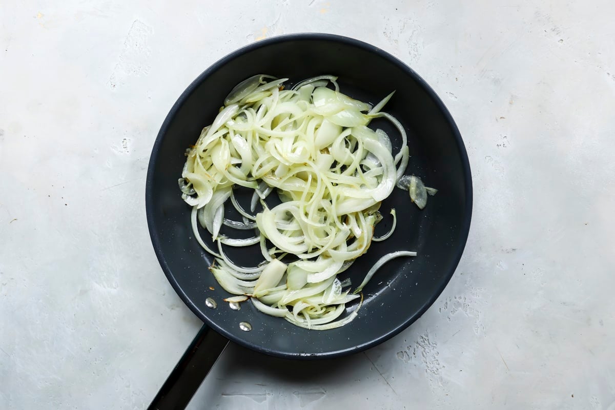 A skillet of onions cooking for eggplant curry.