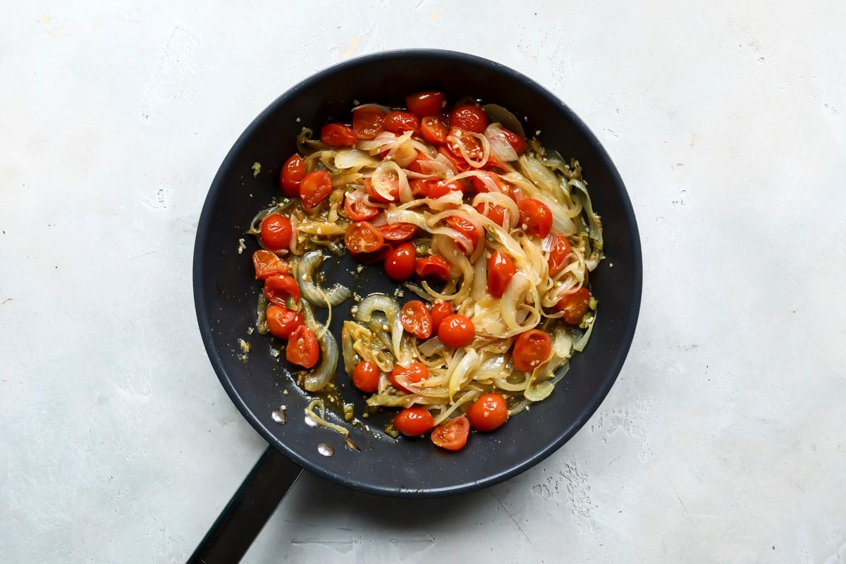 A skillet of onions and tomatoes cooking for eggplant curry.