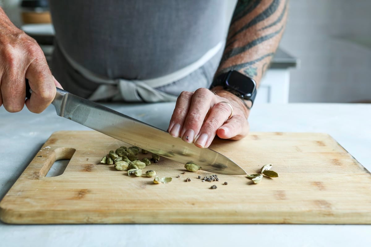 Cutting open cardamom pods to remove the seeds inside.