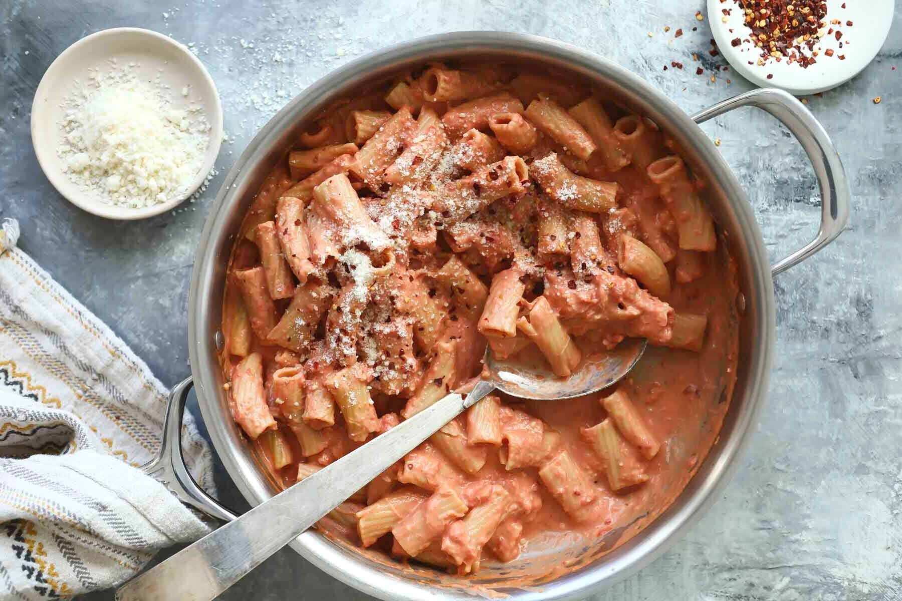 A spoon resting in a pan of penne alla vodka.