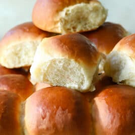 A cooling rack with soft yeast dinner rolls on it.