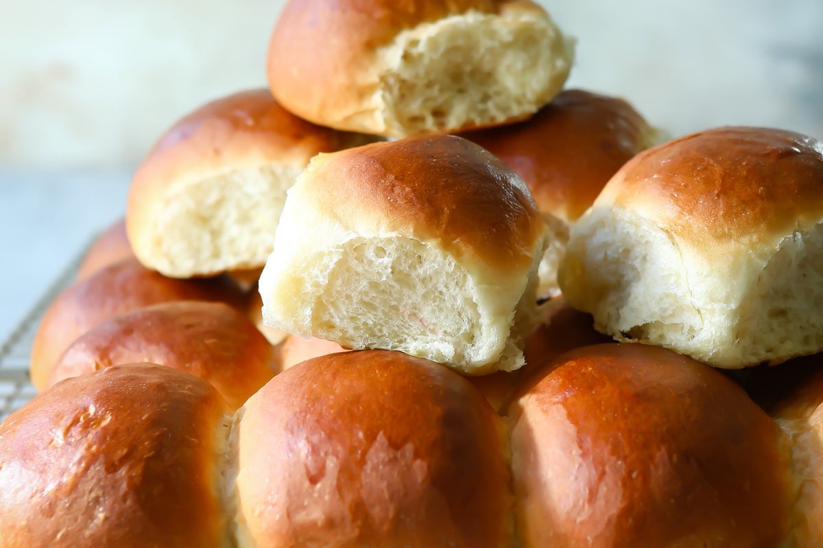 A cooling rack with soft yeast dinner rolls on it.