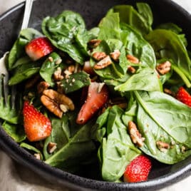 Strawberry spinach salad in a black bowl.