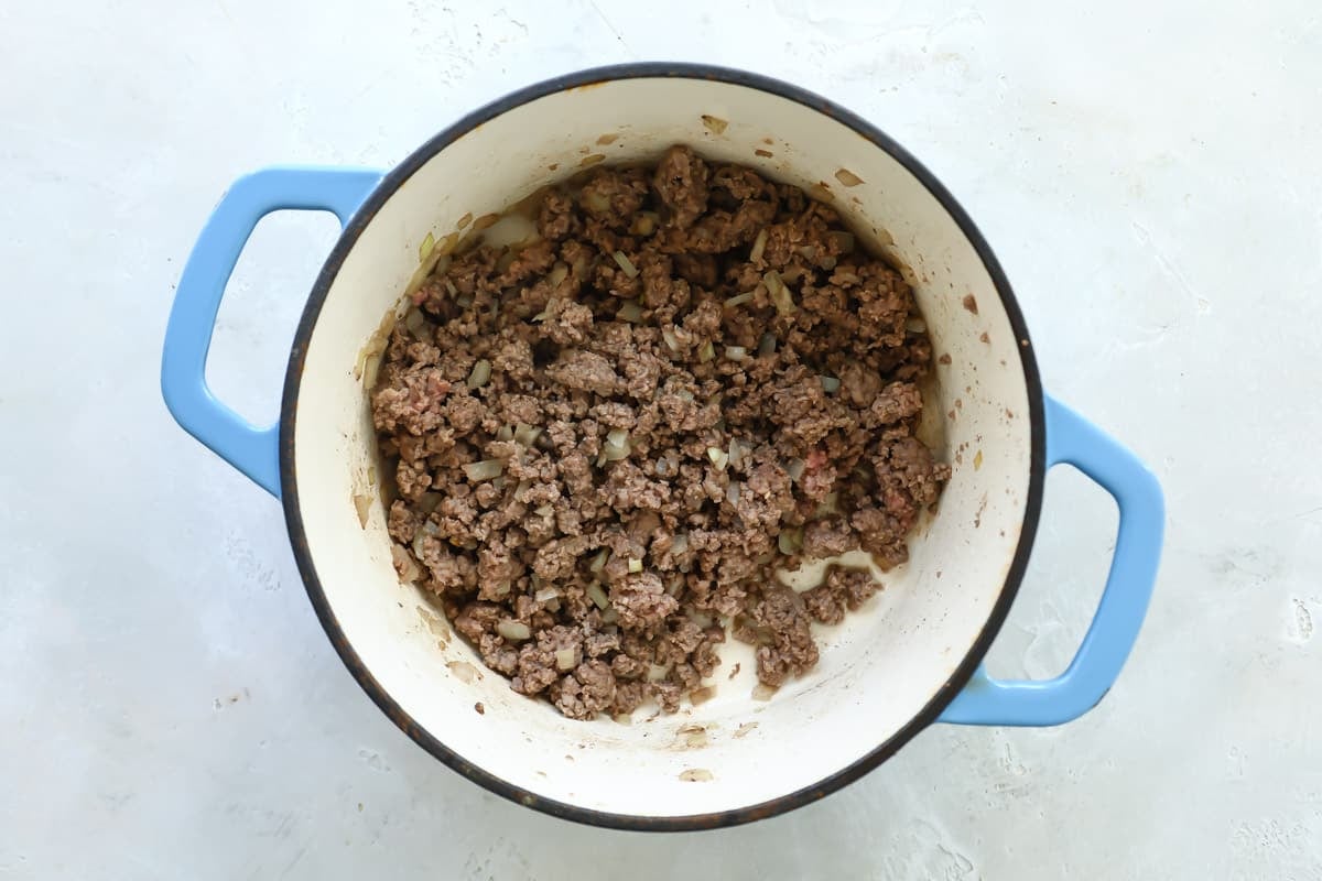 Ground beef and onions cooking in a Dutch oven.