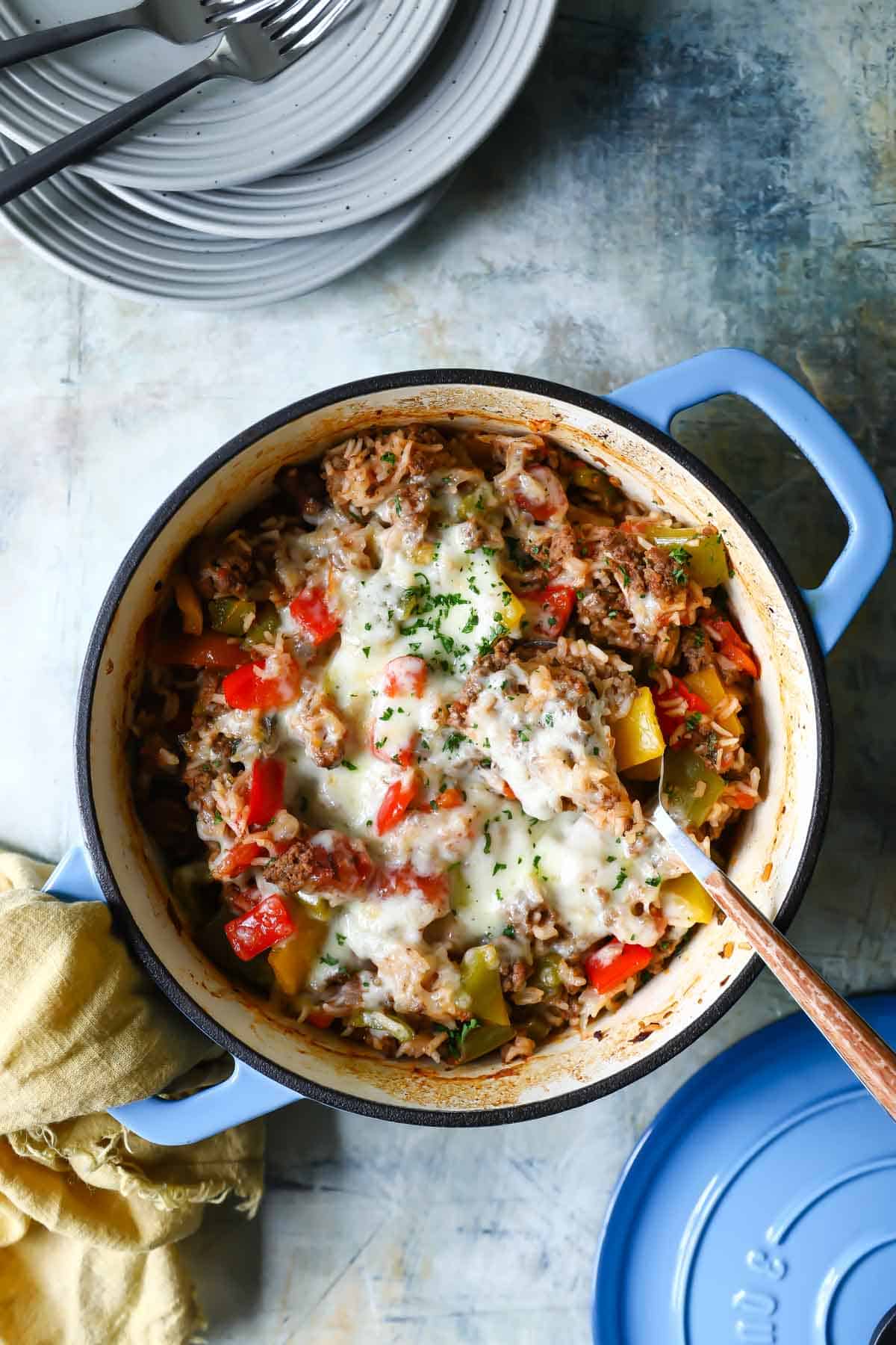 A spoonful of stuffed pepper casserole being scooped out of a Dutch oven.