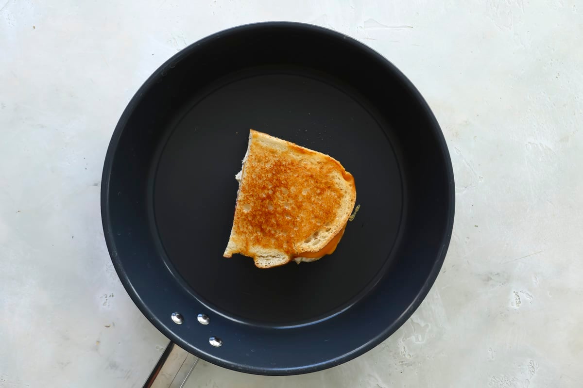 A tuna melt being cooked in a frying pan.