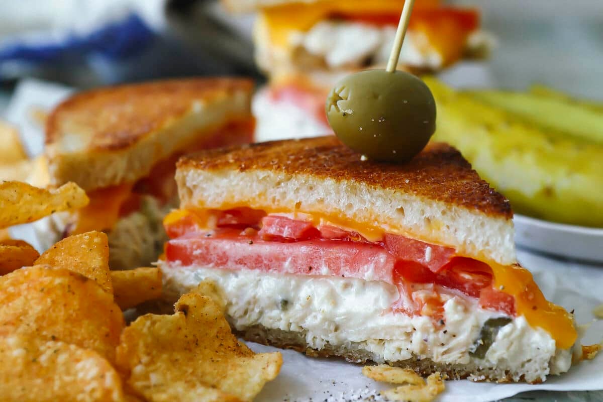 A halved tuna melt on parchment paper next to kettle chips.