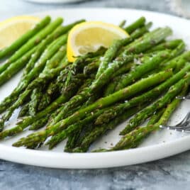 A plate of air fried asparagus with two forks.