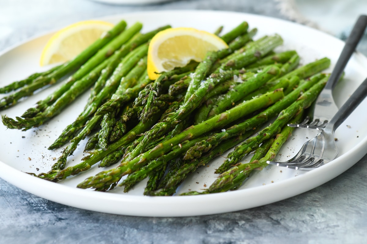 A plate of air fried asparagus with two forks.