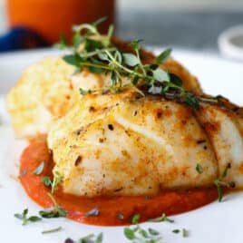 A piece of air fryer cod served over romesco sauce.