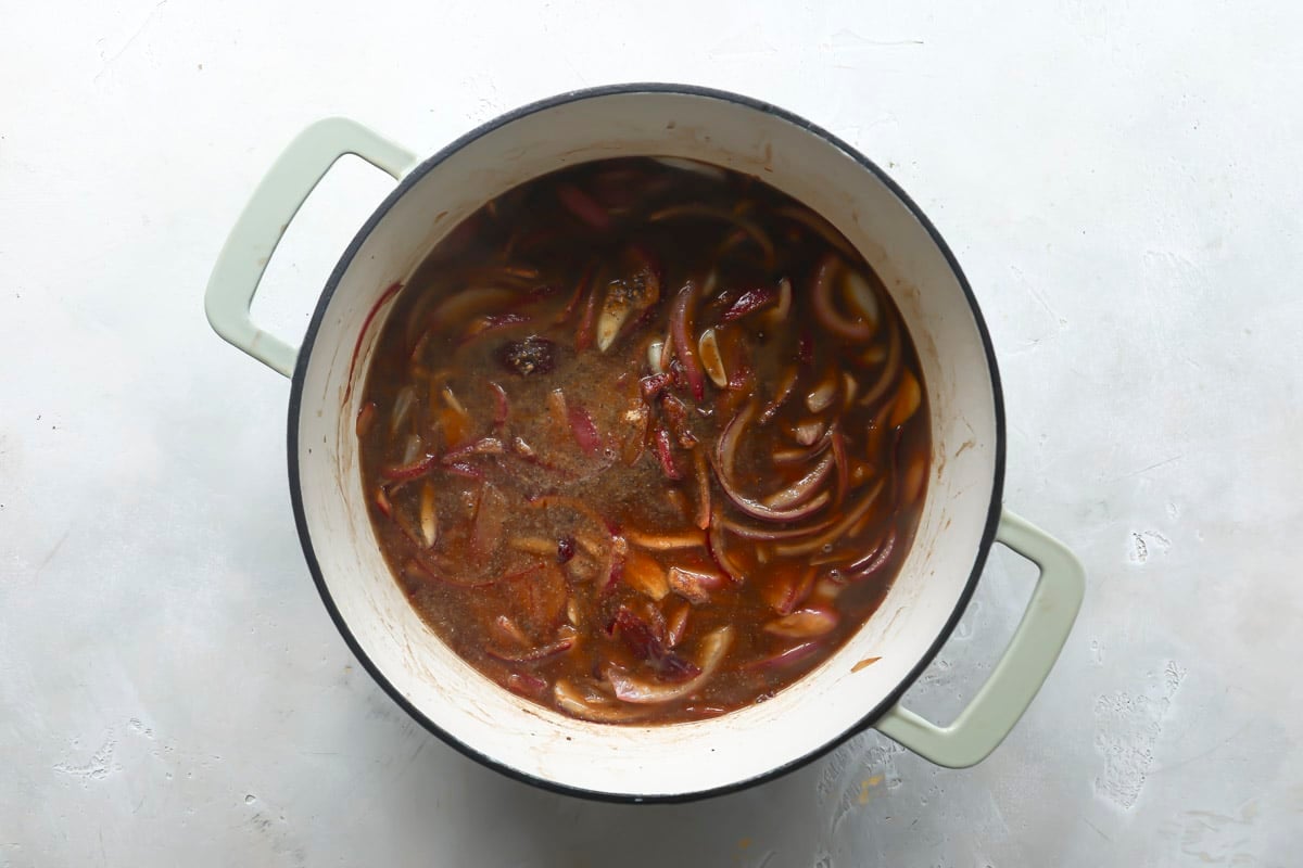 Onion, garlic and bay leafs cooking in vinegars in a Dutch oven.