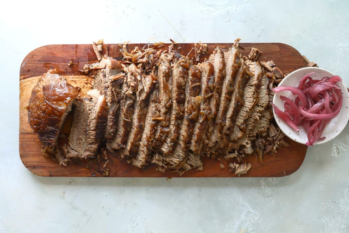 Slices of braised beef brisket on a wooden cutting board.