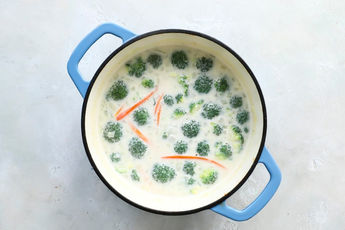 Broccoli cheese soup in a Dutch oven after adding broccoli.