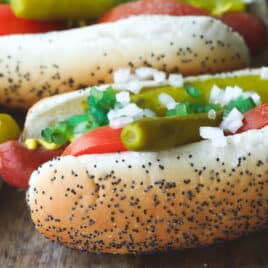 Four Chicago style hot dogs on a wooden platter.