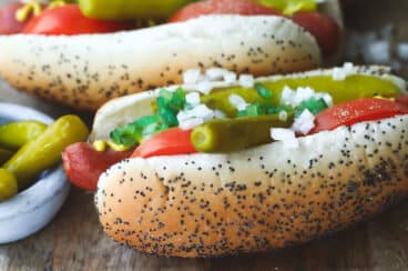 Four Chicago style hot dogs on a wooden platter.