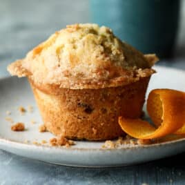 A cranberry muffin on a plate with coffee nearby.