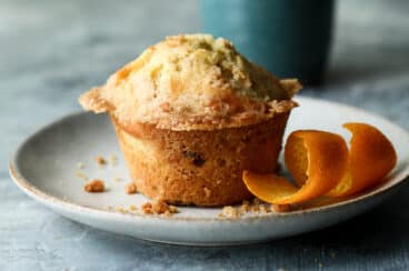 A cranberry muffin on a plate with coffee nearby.